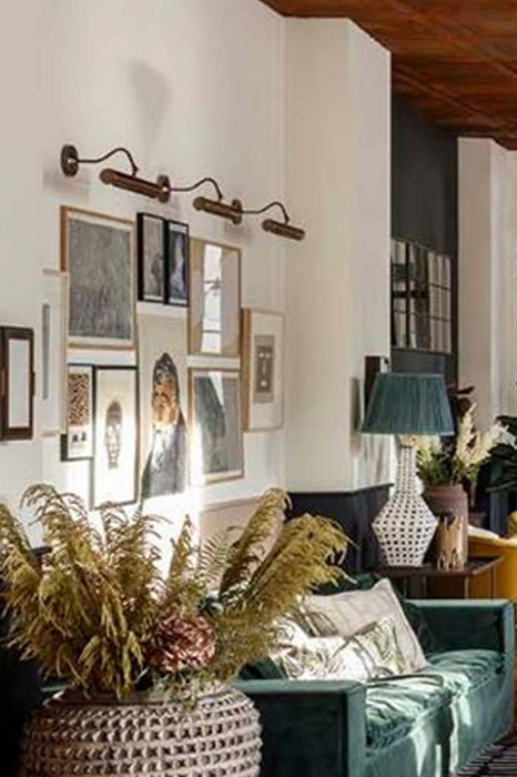 Three brass wall lights positioned above artwork frames in the room.