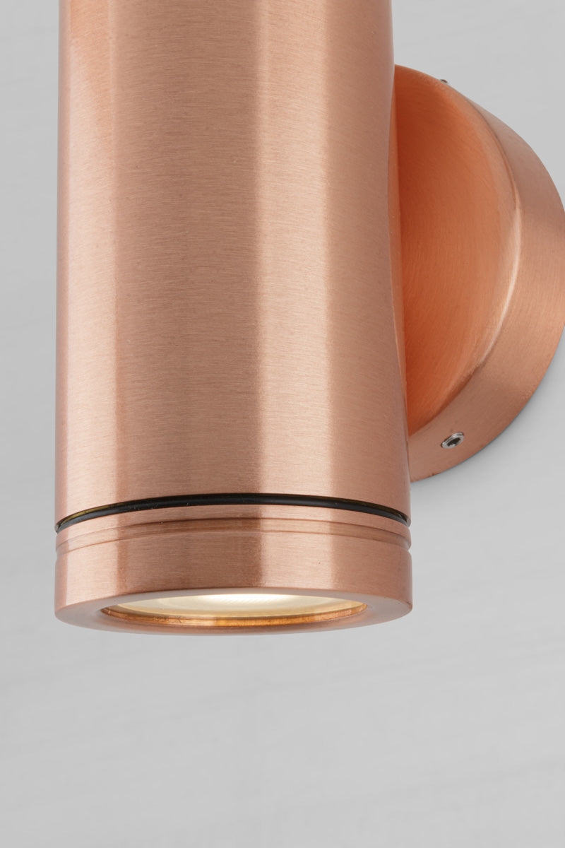 Close up of the lower light of the solid copper up/down wall spot light with a polished finish. 