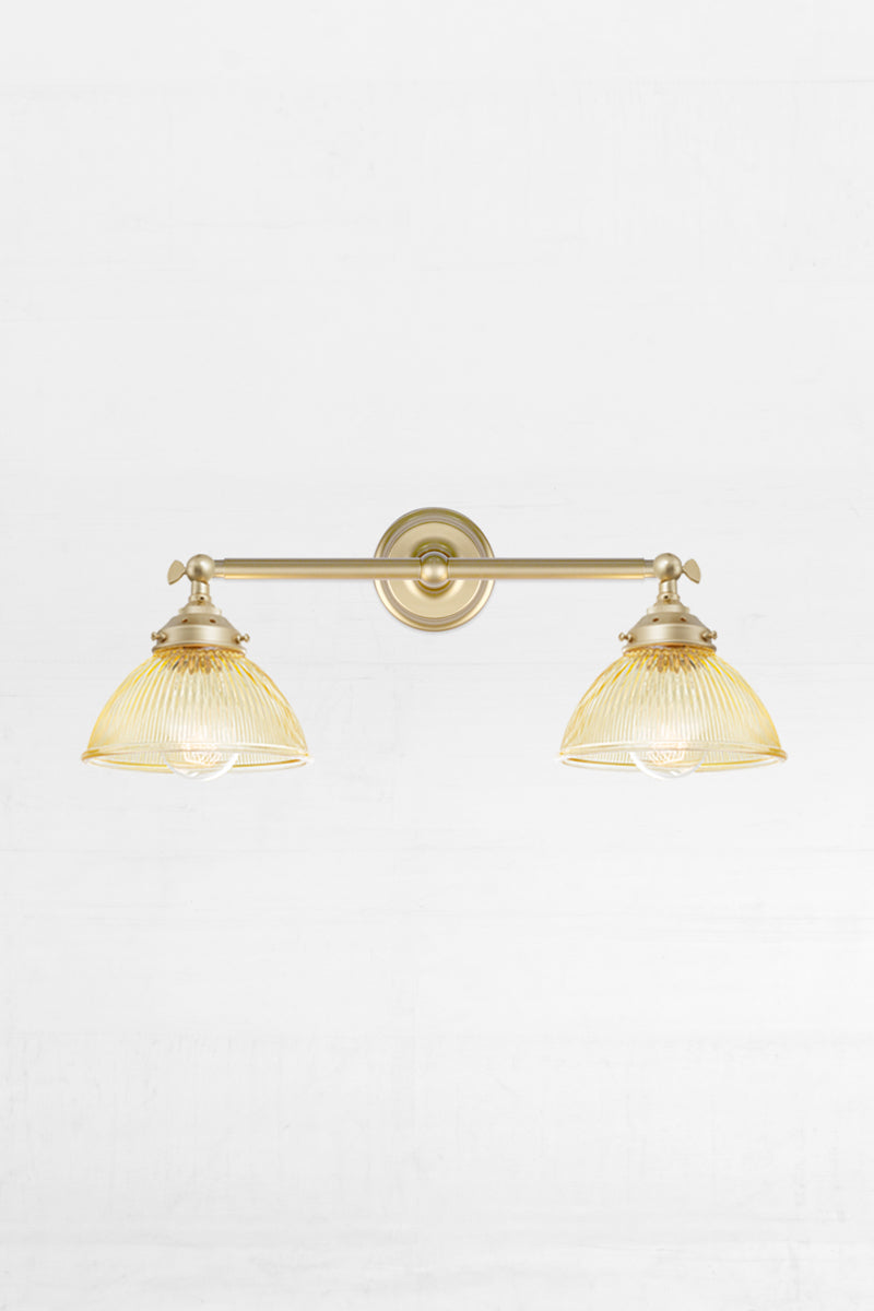 Gold/brass swivel lampholder wall sconce with two amber ribbed glass shades. 