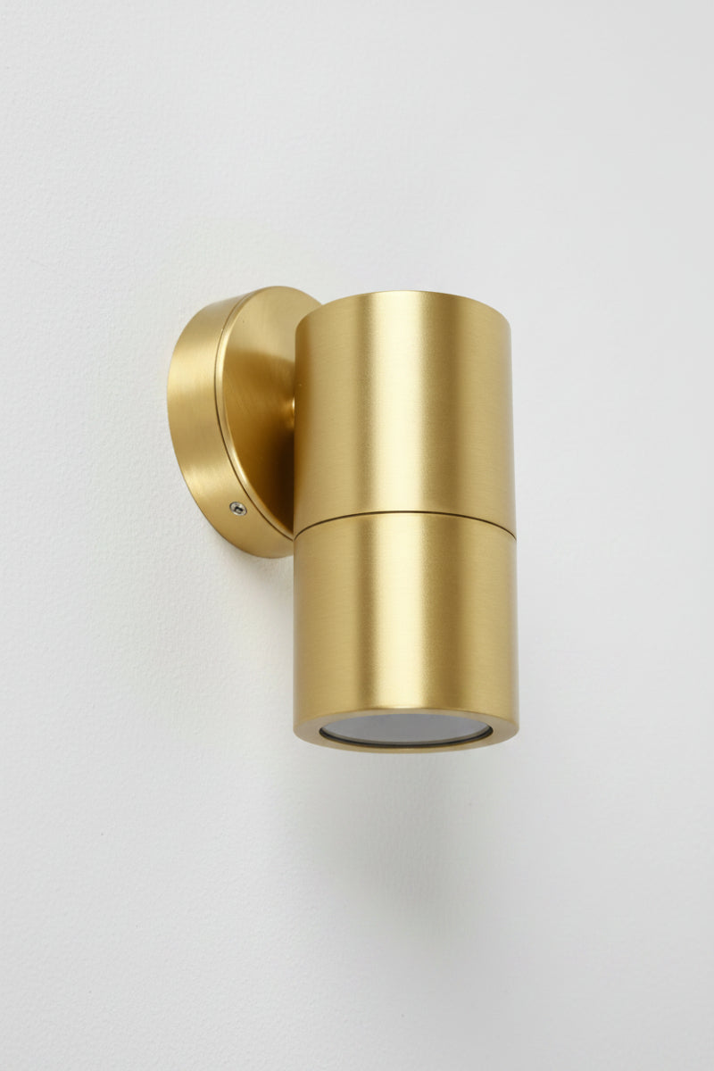A fixed single light wall fixture with a polished brass finish. 