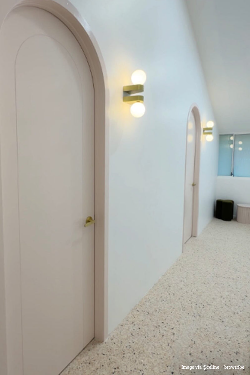 Hallway with arched doorways and double wall lights in gold brass