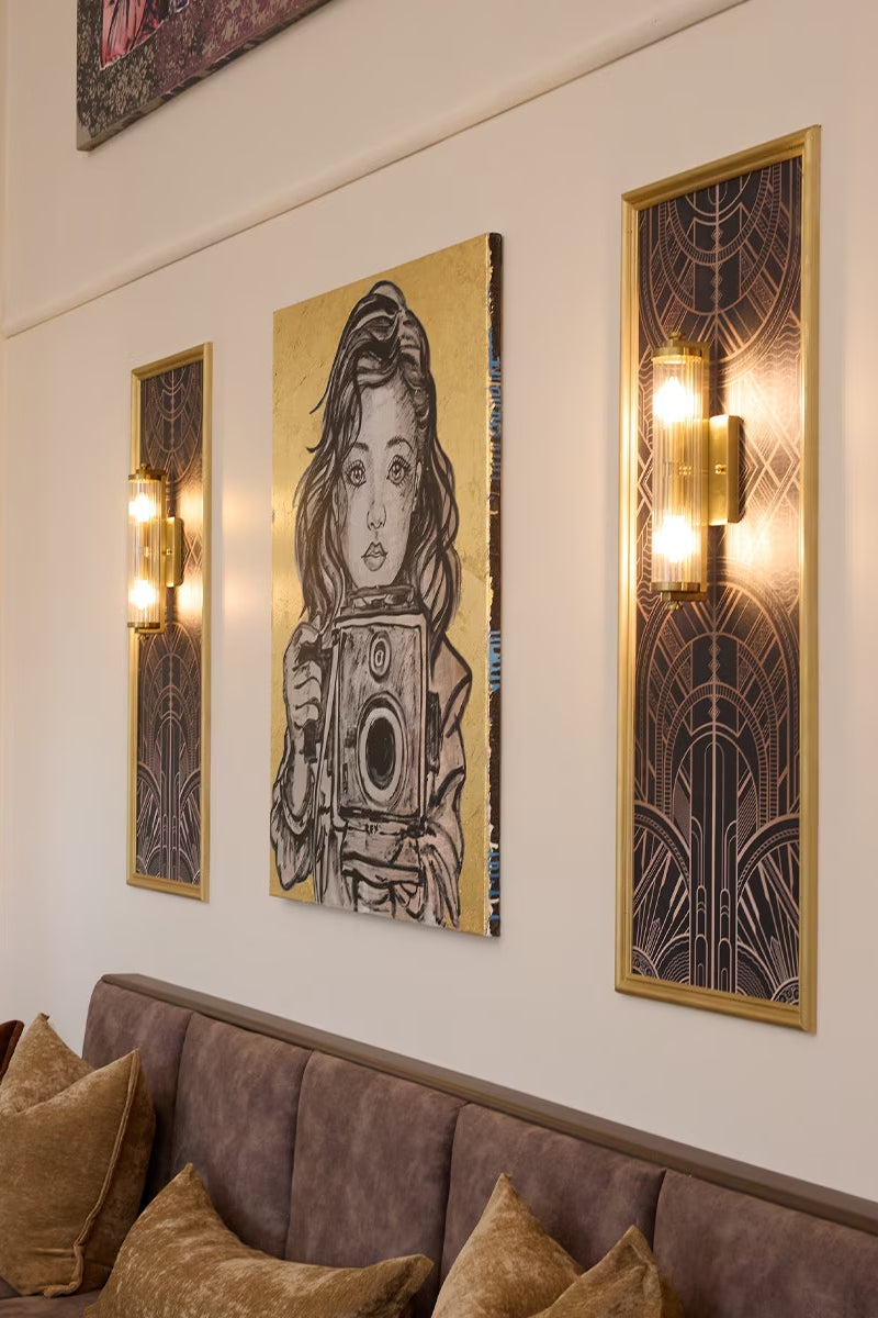 Two Antique Brass wall sconces with reeded glass either side of modern art work. 