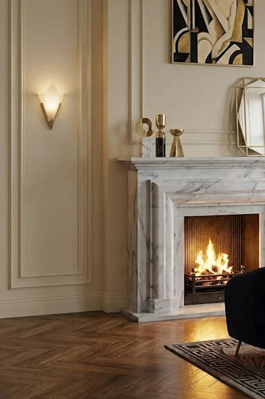 A  Ritz Deco Glass Wall Light lit up and affixed next to a marble fireplace. 