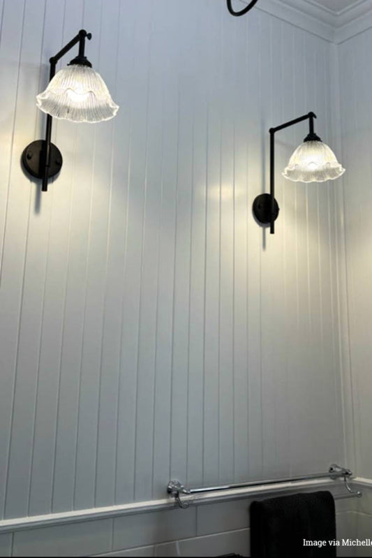 Two wall-mounted como frill glass lights in room on a white paneled wall.
