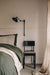 Black swing arm wall sconce hanging next to a bed.