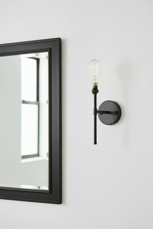 Stem wall light in black offers accent lighting next to mirror
