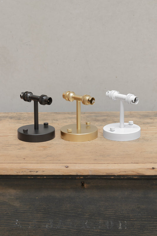 Double Wall Sconce Light in three finishes uninstalled sitting on a timber bench. 