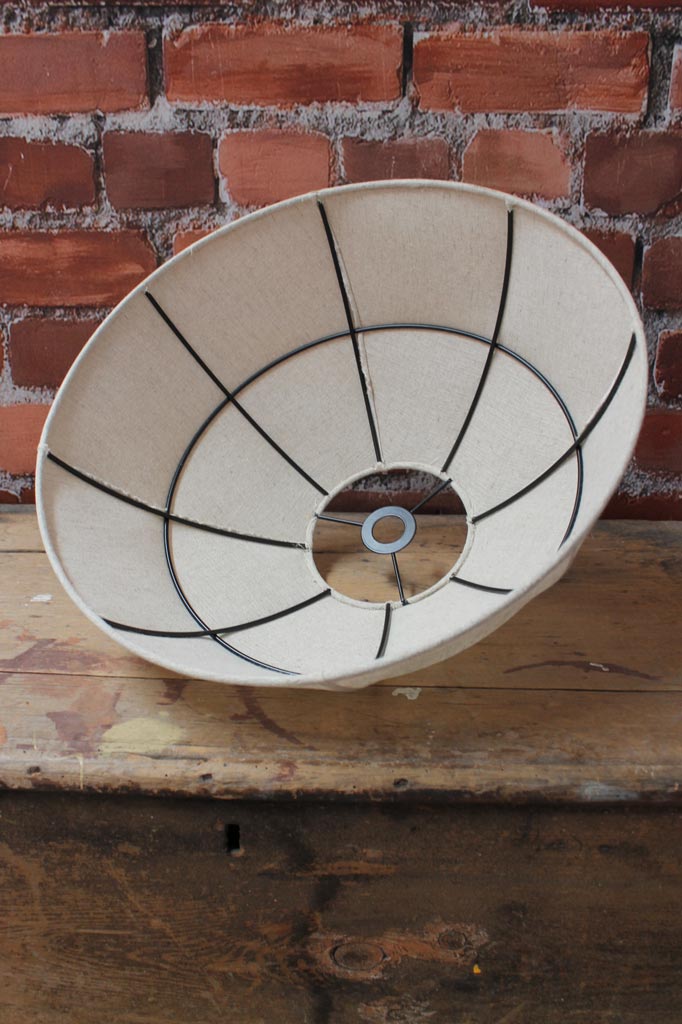Beige fabric shade on a lack frame, placed upside down on a timber bench. 