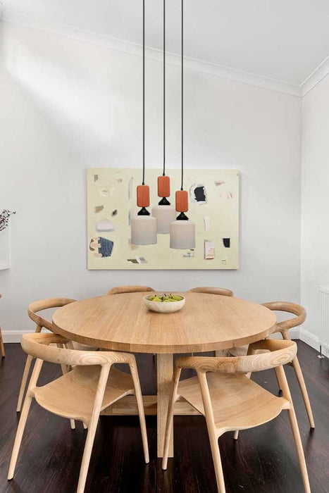Three ceramic pendant lights with wooden blocks hanging over a dining table