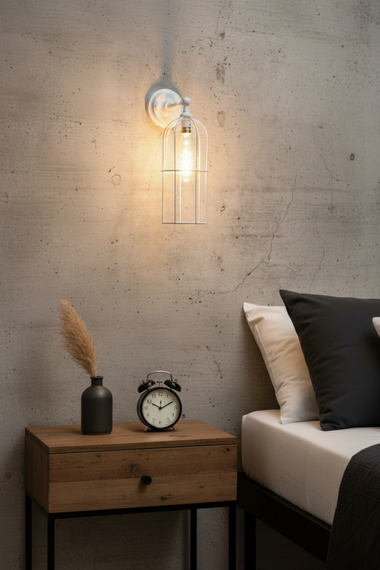Wall-mounted light fixture with wire cage design on a concrete wall near bedside