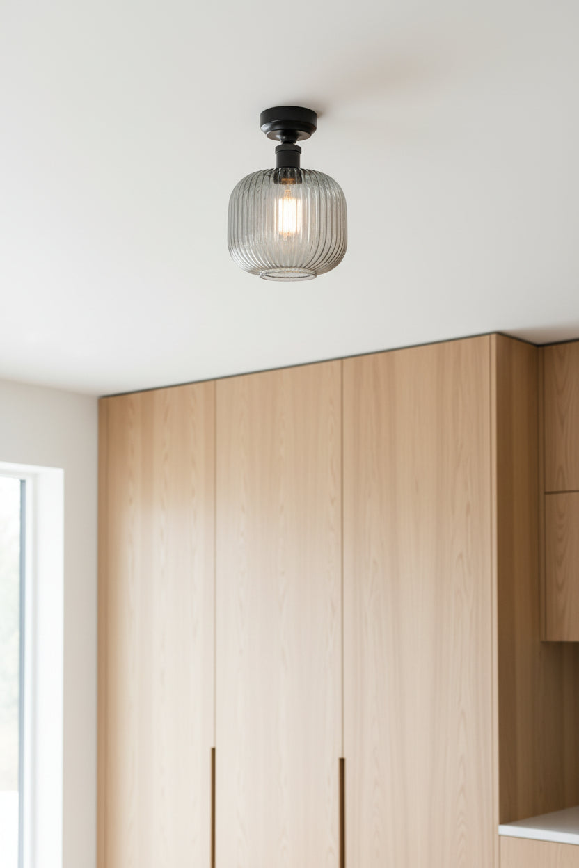 Grey reeded glass shade and black batten holder in a room woth cupboards to the ceiling and lots of natural light. 