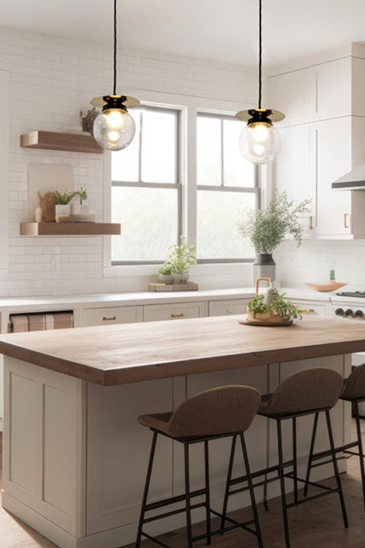 two glass clear pendant lights with brass discs over kitchen island