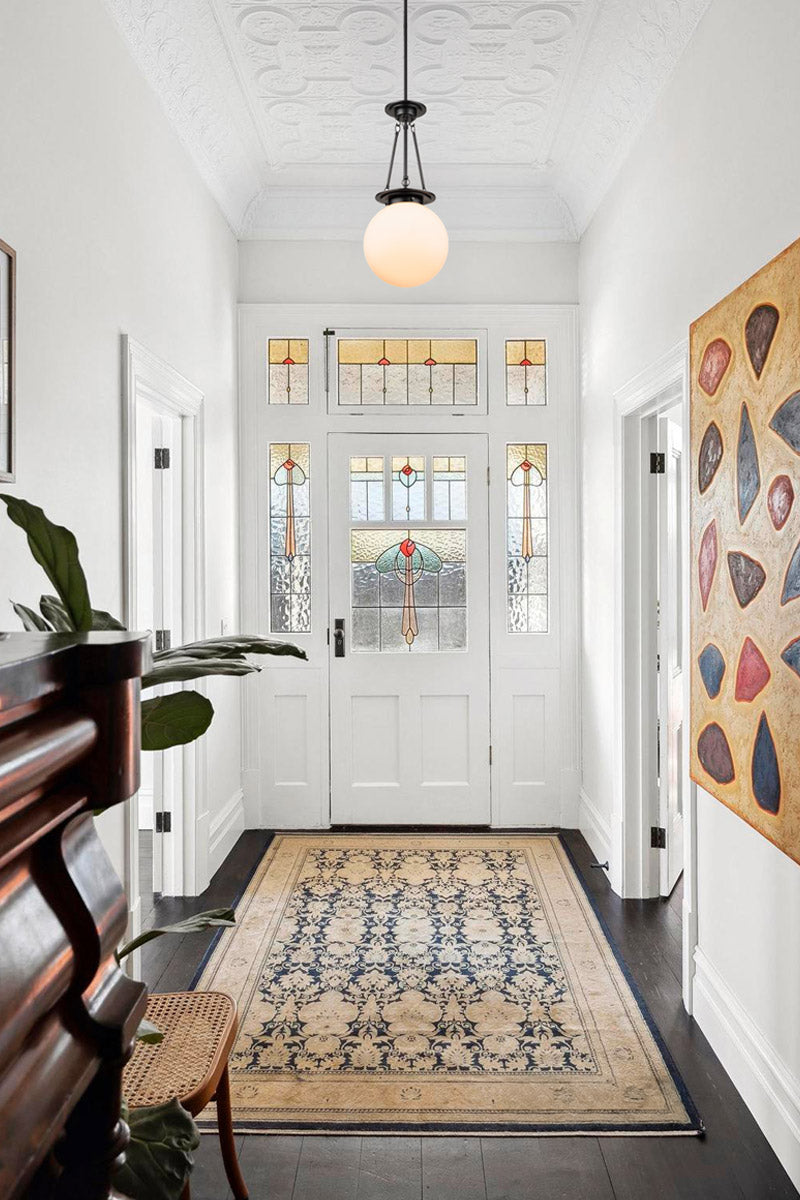 Opal glass shade on a black metal ware pendant in a heritage style entryway. 