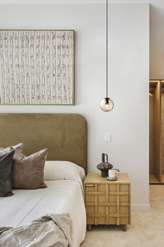 Singe pendant light with an amber, dimpled glass ball shade as a bedside light. 