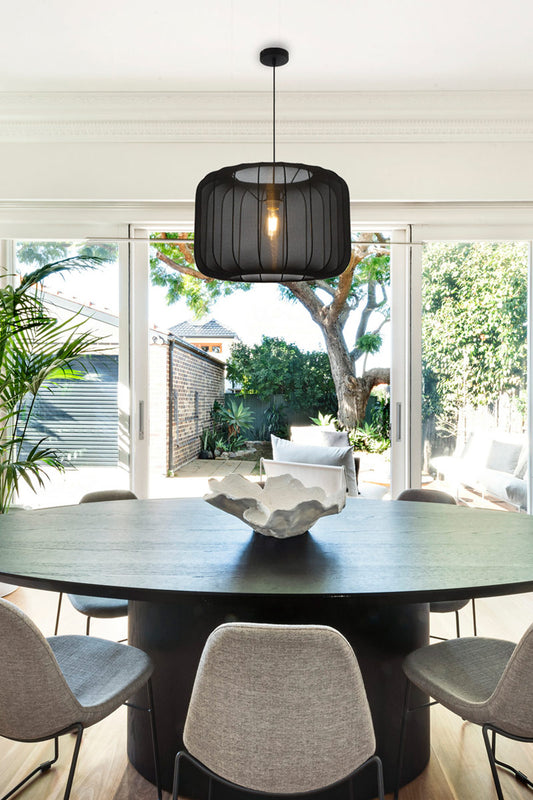 Large black stretch fabric pendant light on circular frame over a modern dining space.