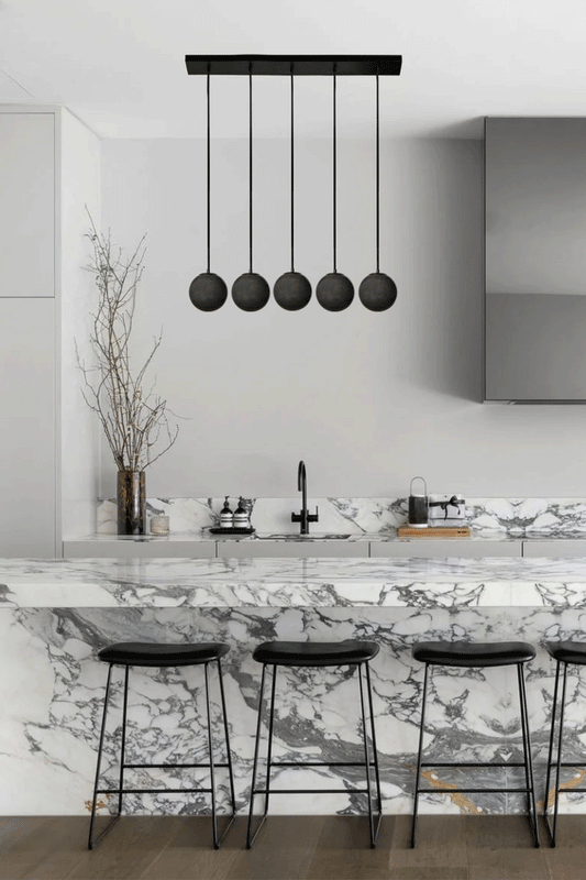 Five drop linear light with black cords and dark grey glass ball shades. 