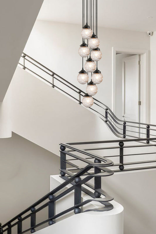 Dramatic nine drop black pendant fixture , with Mid-Century Modern, clear glass orb shades- over a mondern dining space. 