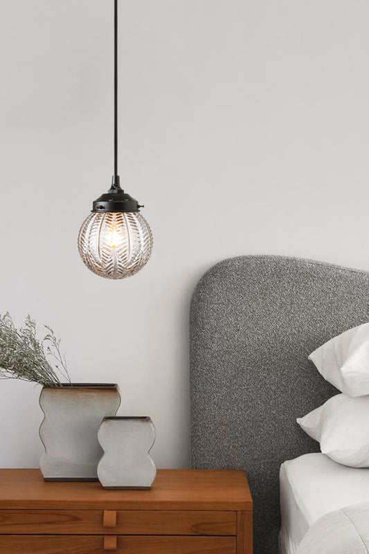 Glass ball shade with deco design on black pendant cord in a bedroom 