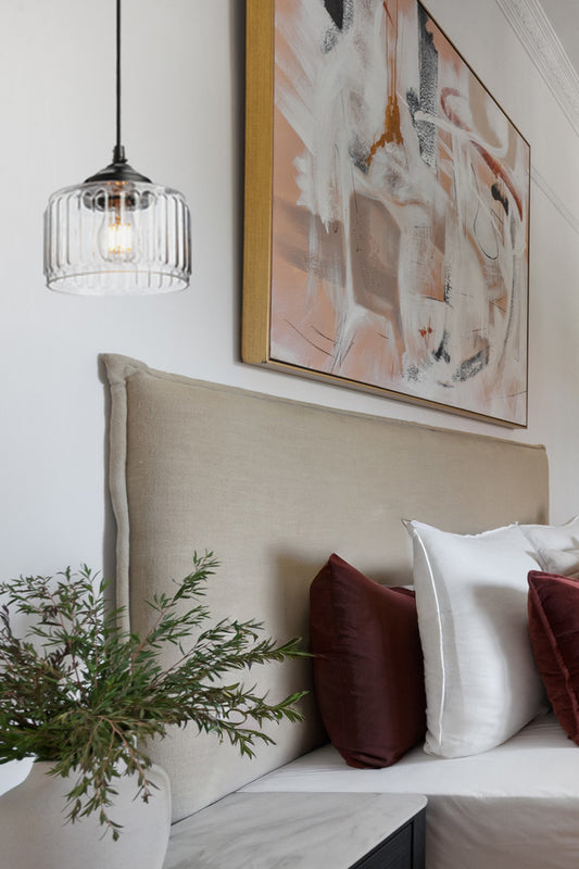 Clear glass shade with thick vertical detailing on a black pendant cord, installed in a contemporary bedroom.
