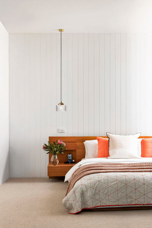 Clear glass shade with a chevron pattern and gold/brass gallery and rose in a fresh modern bedroom with timber and orange tones. 