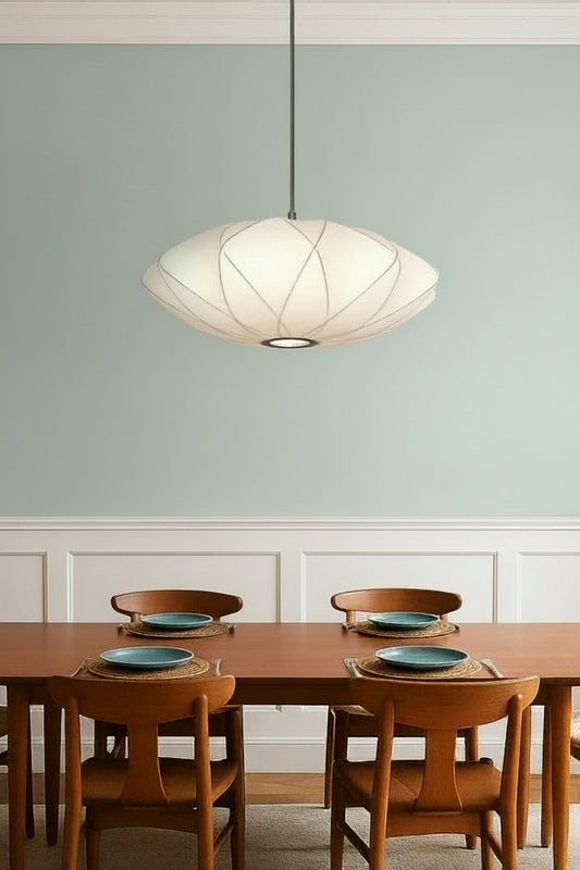 Large white fabric pendant light over a dining space with a salmon coloured wall. 