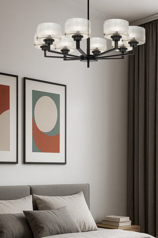 Black 8 light chandelier with clear reeded open glass shades in a clean modern bedroom space. 