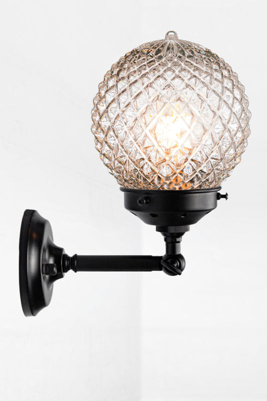 Vintage detailed, clear, glass orb shade on a short straigh wall sconce in black with a swivel lampholder. 