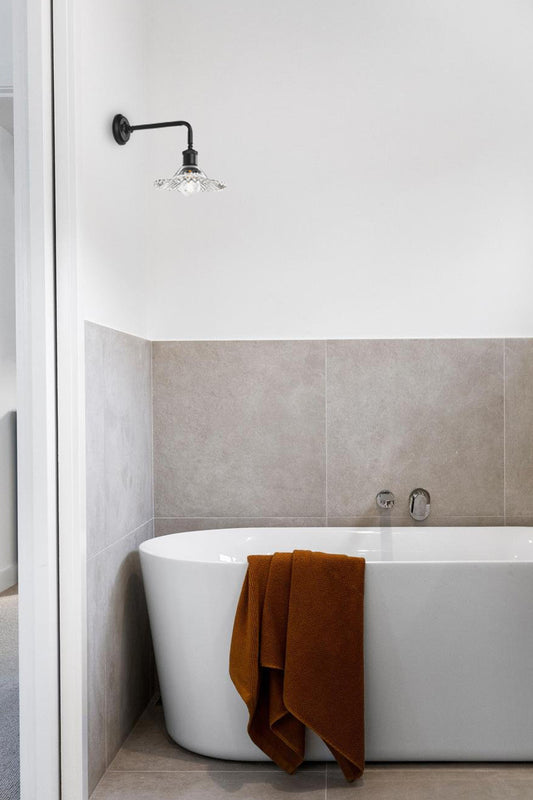 90 Degree wall sconce with a clear pleated glass shade in a modern bathroom. 