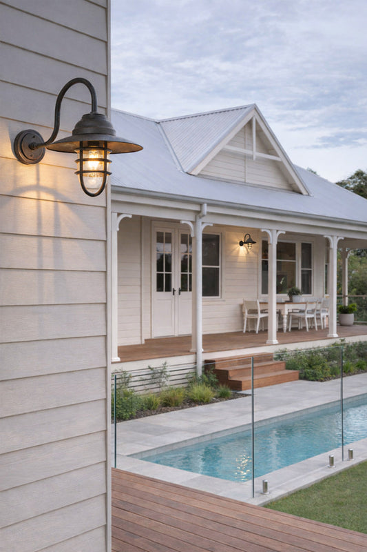 Gooseneck cage light in Antique Broze on a classic Australian weatherboard house next to a pool area. 