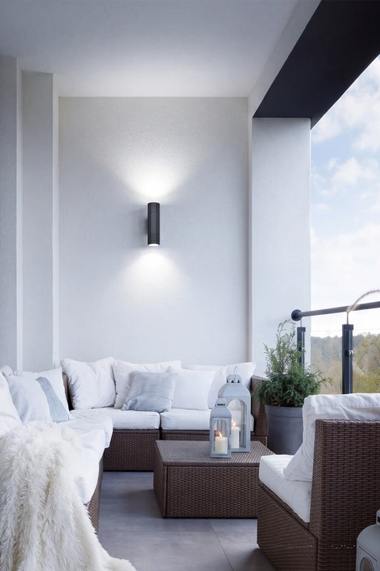 Black up down exterior spotlight on a balcony wall above outdoor lounge seating