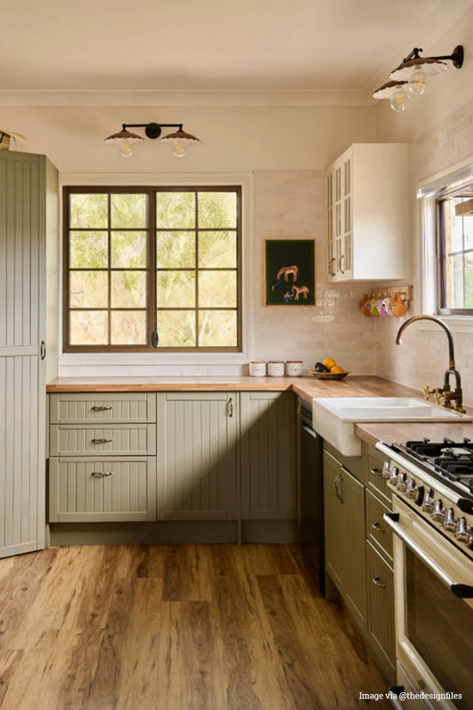 Image from @thedesignfiles instagram page showing two double arm wall sconces with metal umbrella shades in a renovated vintage style kitchen. 