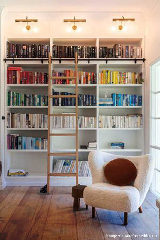 3 Polished brass picture lights over a bookshelf. 