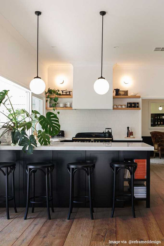2 glass ball pole pendant lights over a kitchen bench.