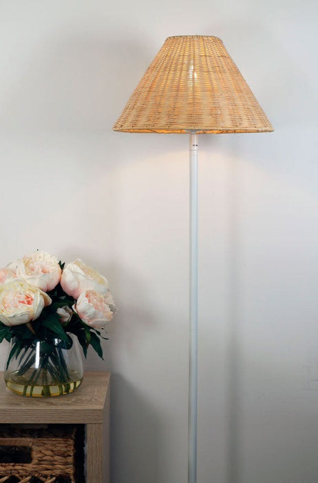rattan floor lamp next to a bedside table.