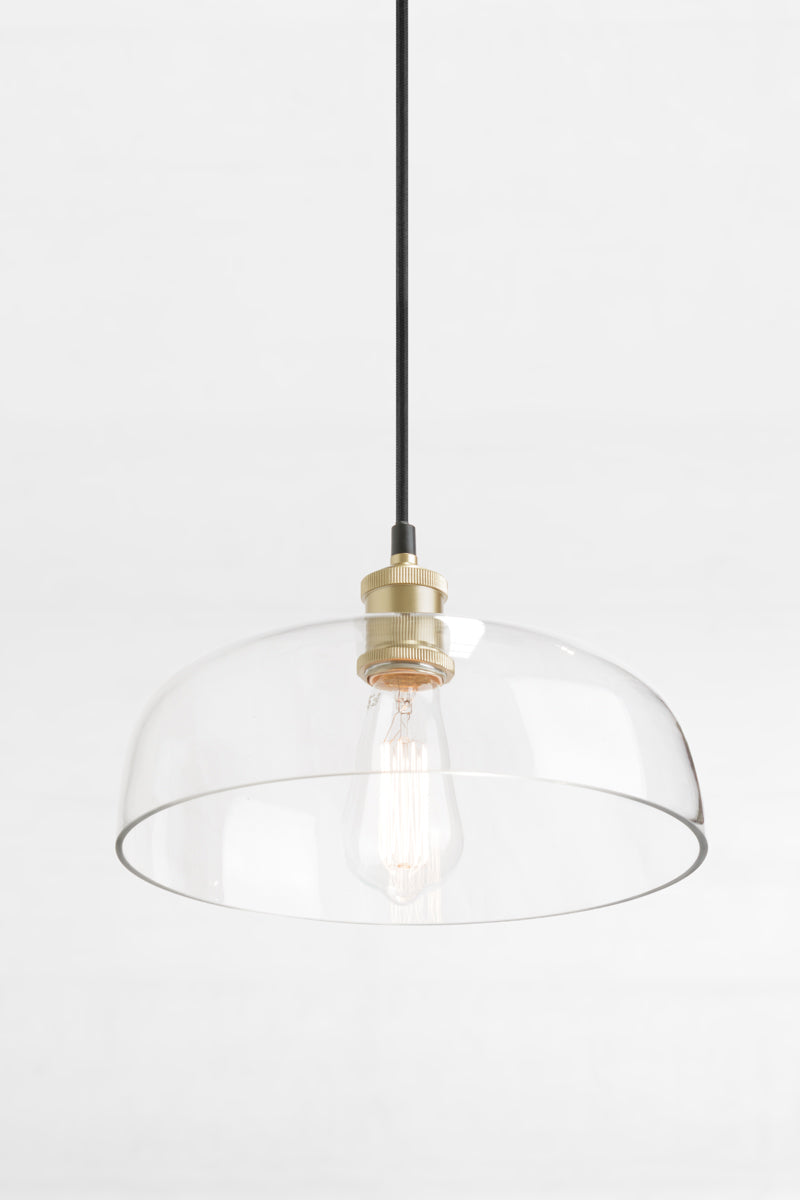 Clear glass shade with black cord and gold/brass lampholder. 