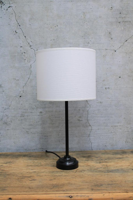 Black table lamp with white fabric shade turned off