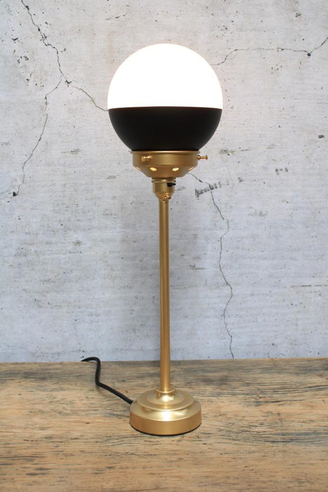 Table lamp with black shade and gold base and gallery