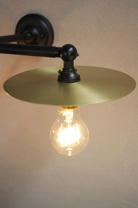 Black wall light with small brass disc