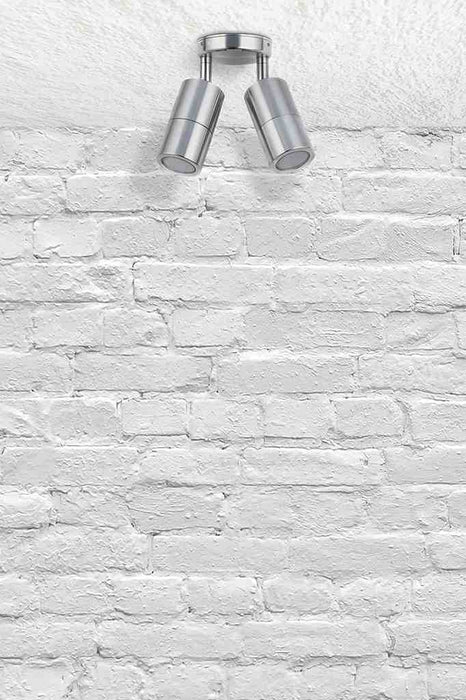 Twinlight spotlight in titanium affixed on a brick wall.