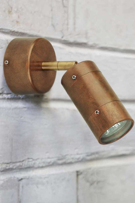 Copper wall light affixed on brick wall. 