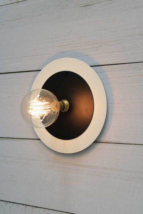 Large white disc with small black wall light
