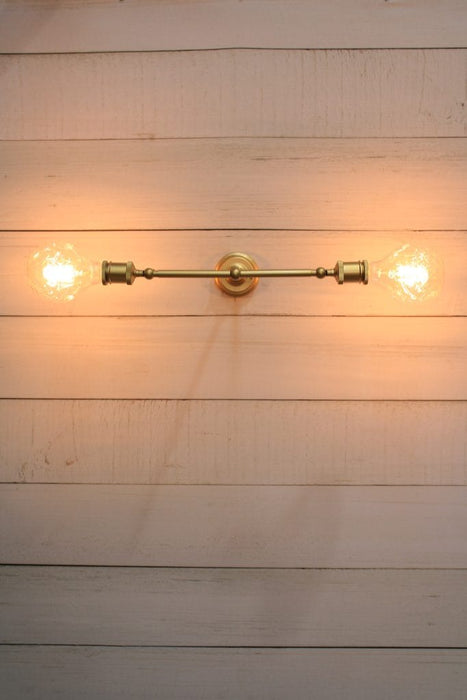 Double arm wall sconce in gold tilted horizontally