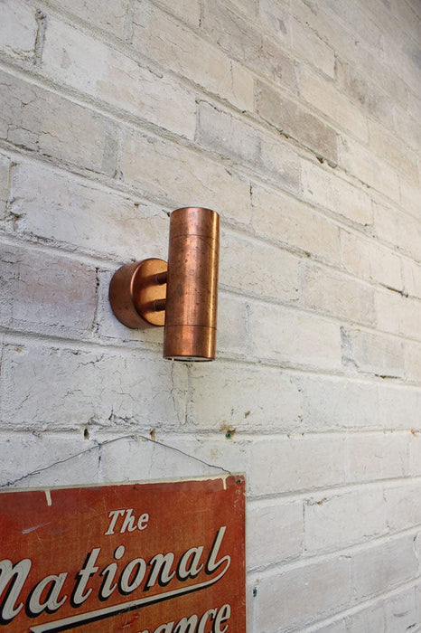 Double copper wall light affixed on brick wall. 