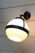 Huxley wall light with short black arm and medium open bottom shade in tilted position