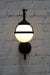 Wall light with black swivel arm and opal glass ball shade with metal band