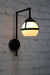 Wall light with black swivel arm and open opal glass ball shade with metal band