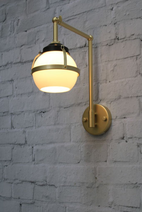 Wall light with gold/brass swivel arm and open opal glass ball shade with metal band