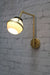 Wall light with gold/brass swivel arm and open opal glass ball shade with metal band
