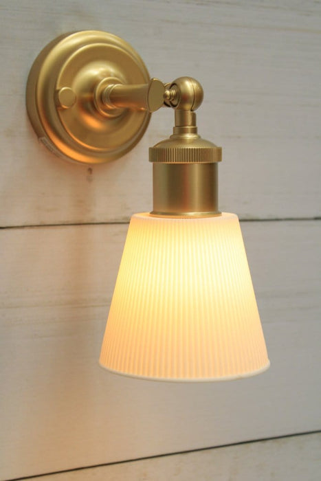 Gold/brass wall light with small ceramic shade