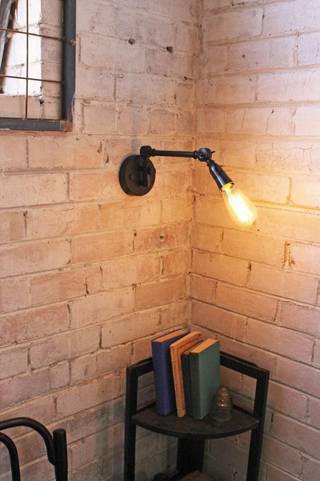Industrial swing arm wall light with teardrop edison bulb.